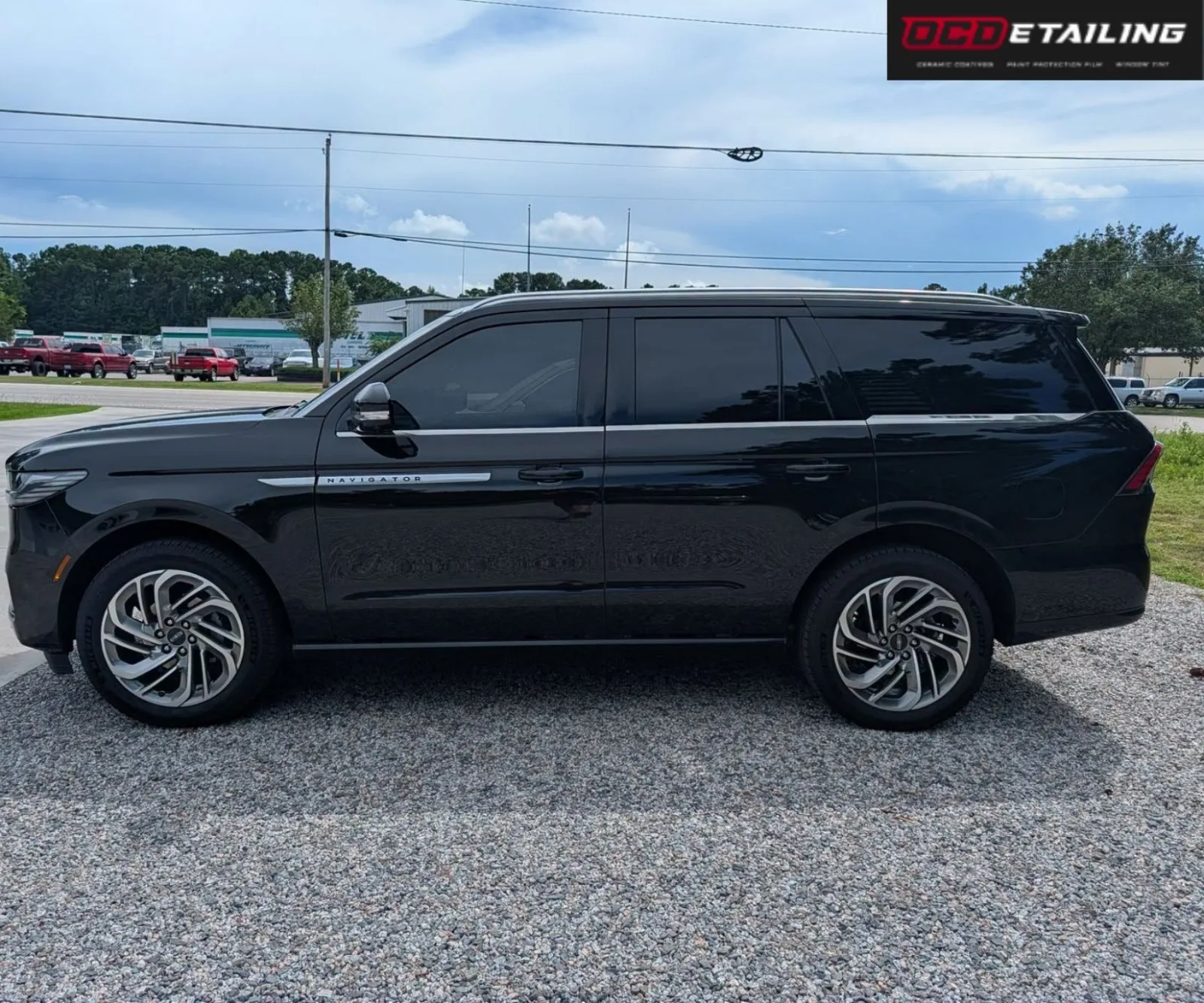 Full side profile view of a black Lincoln Navigator parked outdoors on a gravel lot.