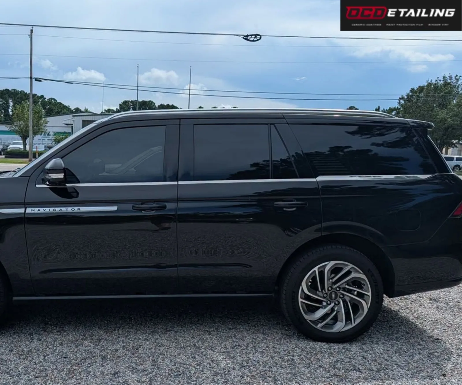 Closer side view focusing on the dark tinted windows and front door emblem of a black Lincoln Navigator.