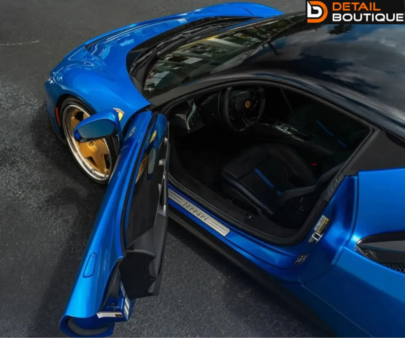 High-angle shot looking down into the open driver-side door of a blue Ferrari supercar.